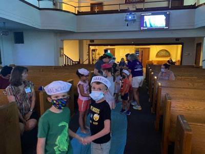 Kids standing in the middle isle of the sanctuary with sailor hats on