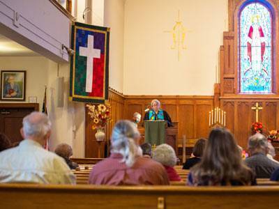 Pastor Katie preaching from the pulpit. Photo is taken from seated position in sanctuary.