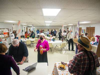 Church members in room with white tiled floor, with tables