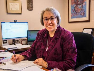 Pastor Katie Estes smiling at the camera with a computer in the background